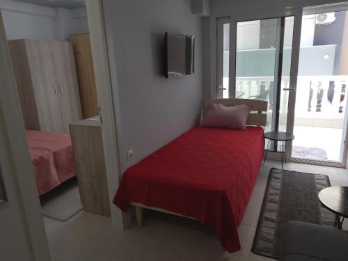 a small bedroom with a bed with a red blanket at Lana in Paralia Katerinis