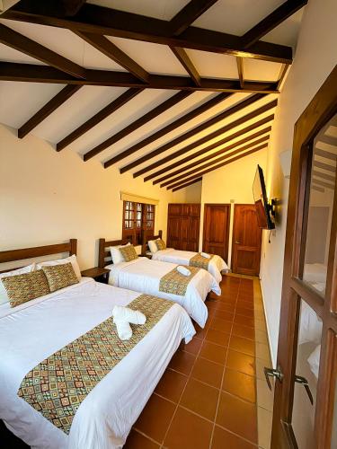 a row of four beds in a room at Yeshca Hotel Boutique in Villa de Leyva