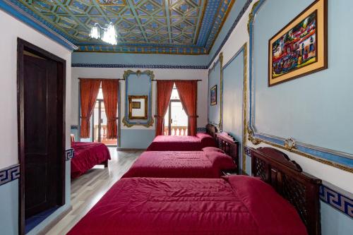 a room with four beds with red sheets at Hotel Majestic 1 Centro Histórico Cuenca in Cuenca