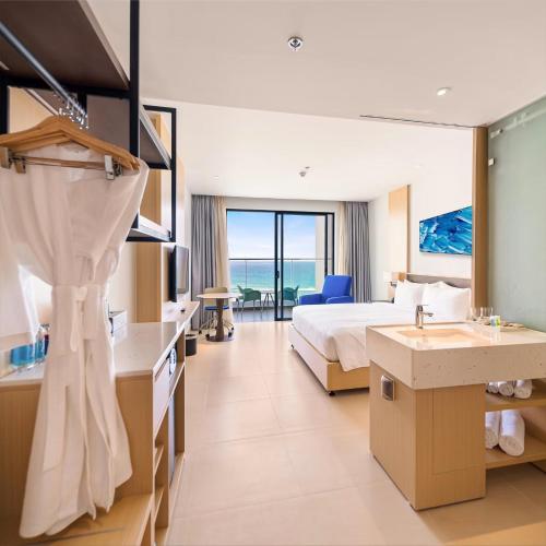 a large hotel room with a bed and a sink at Hanna Seaview Stella - The Arena Resort in Cam Ranh International Airport