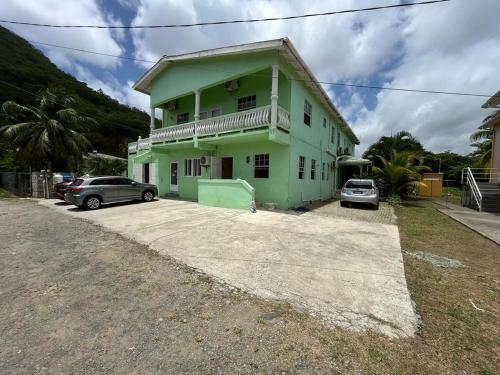 a green house with cars parked in front of it at Hibiscus Apt 1 in Corinthe
