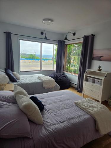 a bedroom with three beds and a large window at Martin's apartment in Saguenay