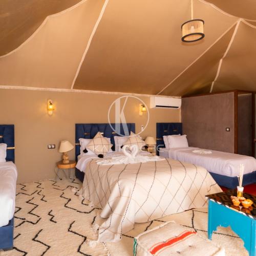 a bedroom with two beds and a rug at Kal Tenere Luxury Camp in El Karia