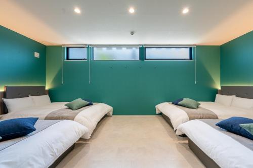 a row of beds in a room with green walls at Universal front villa Sanrriott in Osaka