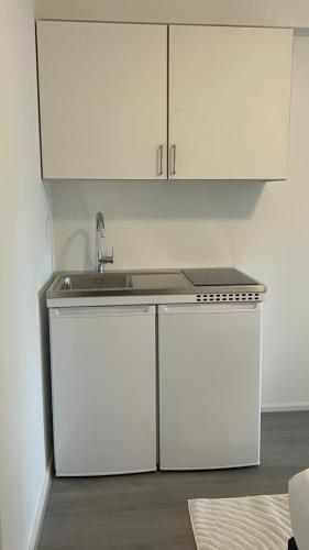 a kitchen with a sink and white cabinets at Ilulissat City Apartments- Apartment 2 in Ilulissat