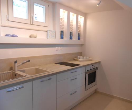 una cocina con armarios blancos y fregadero en HydraVista (Pearl), en Hydra