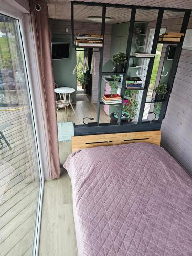 a bedroom with a purple bed and a window at Vaitų Riešutynė - Small shipping container house in Antanava