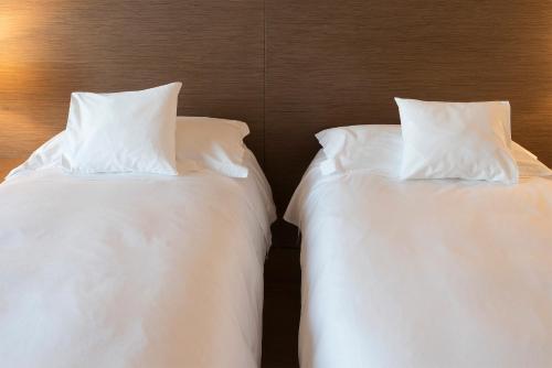 two beds with white sheets and pillows next to each other at Il Porticciolo in Laveno-Mombello