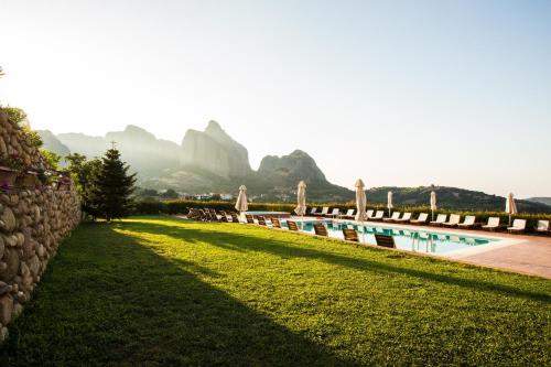 a large swimming pool with a stone wall and grass at Meteora Hotel at Kastraki in Kalabaka