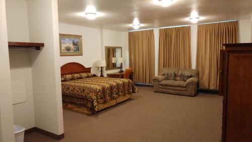 a hotel room with a bed and a chair at Country Regency Inn & Suites in Manvel