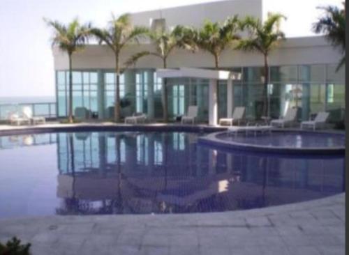 a swimming pool with palm trees in front of a building at Excelente Apartamento Palmetto con vista al mar in Cartagena de Indias