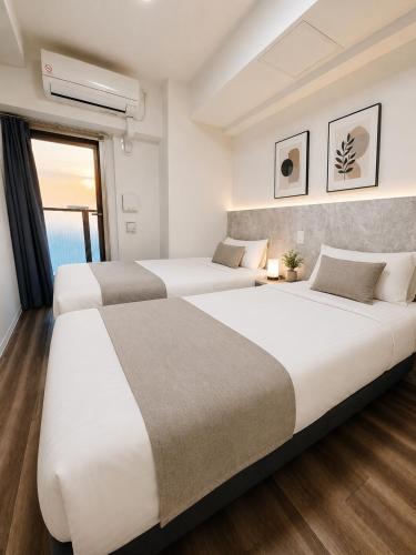 two beds in a hotel room with a window at Hotel Arashi Tengachaya No005 in Osaka