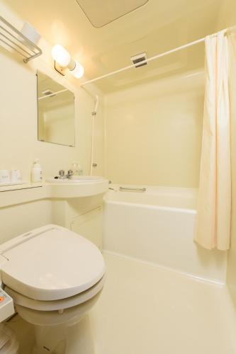 a white bathroom with a toilet and a bath tub at Hotel Soleil in Iwaki