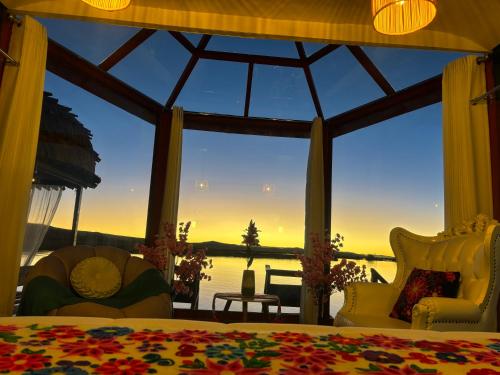 a bedroom with a large window with a view of the water at Titicaca Maya Lodge Perú in Puno