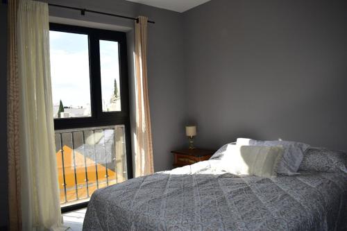ein Schlafzimmer mit einem Bett und einem großen Fenster in der Unterkunft Chihuahua Historic Suite in Chihuahua