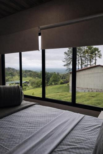a bedroom with a bed and a large window at La Cima Escondida Bijagua Rio Celeste 20 Min in Upala