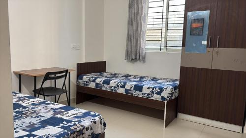 a room with two beds and a table and a desk at Pemmis living space in Bangalore