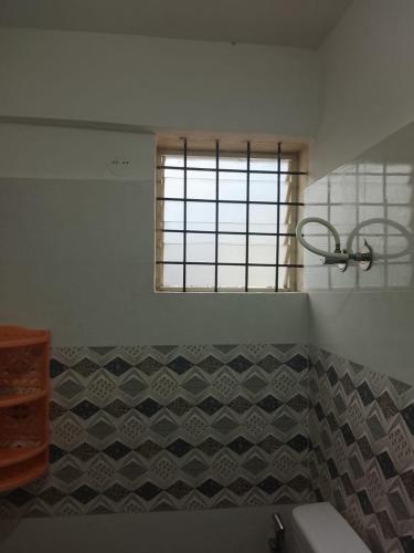 a bathroom with a window and a tiled wall at Pemmis living space in Bangalore