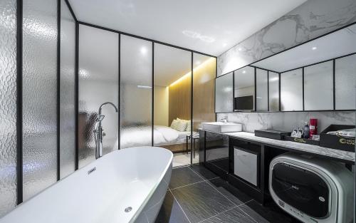 a bathroom with a tub and a washing machine at Cacao Hotel in Incheon