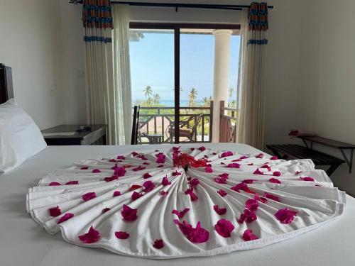a large white bed with pink flowers on it at Alfa Boutique Hotel in Kiwengwa