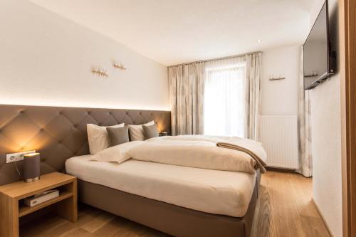 Un dormitorio con una cama grande y una ventana en Slow Living Suite - Ferienwohnung mit privater Sauna & Garten en Fiss
