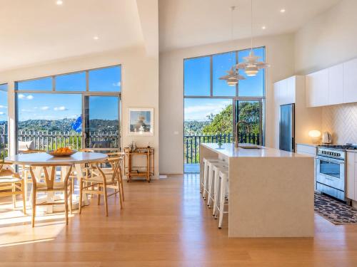 a kitchen and dining room with large windows at Oneroa Vines and Views- Stay Waiheke in Blackpool