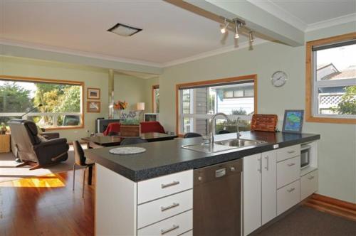 a kitchen with a sink and a living room at Te Moana Delight in Waikanae