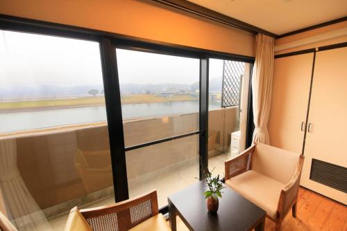 a room with a table and chairs and a large window at Yutorelo Yamaga in Yamaga