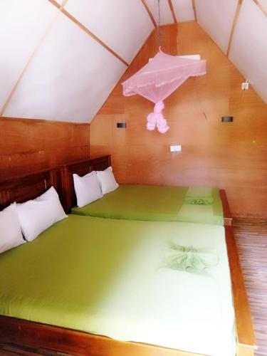 a room with a large green bed with an umbrella at Ceylon Antheia Beach Resort in Nilaveli