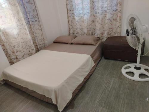 a small bedroom with a bed and a fan at Yannas transient house in Roxas City