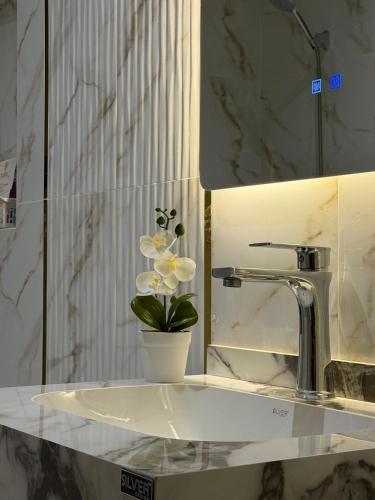a bathroom sink with a vase of flowers on it at شقق واحة المحمدية in Baljurashi
