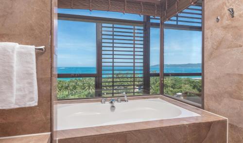 a bath tub in a bathroom with a large window at Yalong Bay Mangrove Tree Resort in Sanya