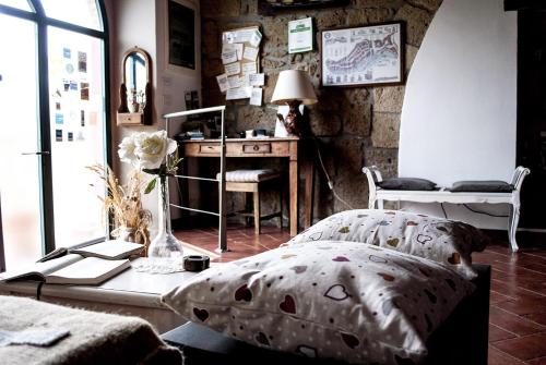 a bedroom with a bed and a desk and a table with a lamp at La Casa dei Carrai in Pitigliano