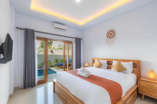 a bedroom with a large bed and a tv at Kubu YN Bali in Jimbaran
