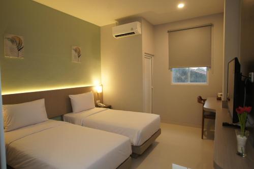 a hotel room with two beds and a window at Hexton Hotel Lampung in Tanjungkarang