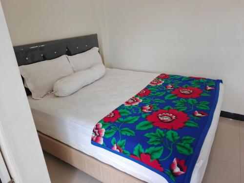 a small bed with a floral blanket on it at Homestay Reyna in Ende Airport