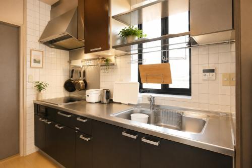 a small kitchen with a sink and a window at ゲストハウスガーデンズmihama in Wada