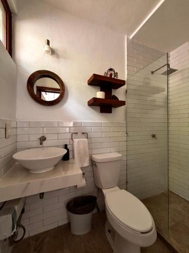 a bathroom with a toilet and a sink and a mirror at Tropical Garden Suites steps from the Lagoon in Bacalar