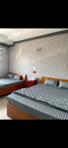 a bedroom with two beds and a wall at Khách sạn Hoàng Đại in Buôn Kuop