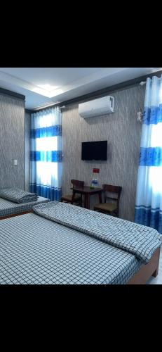 a bedroom with two beds and a table and a television at Khách sạn Hoàng Đại in Buôn Kuop