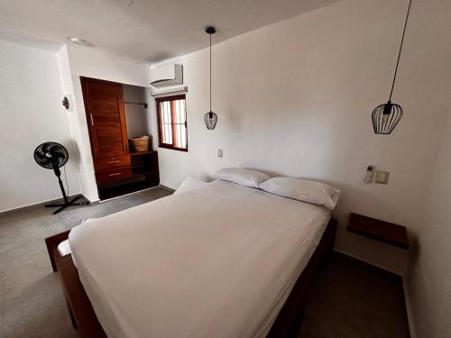 a bedroom with a bed with white sheets and a window at Tropical Garden Suites steps from the Lagoon in Bacalar