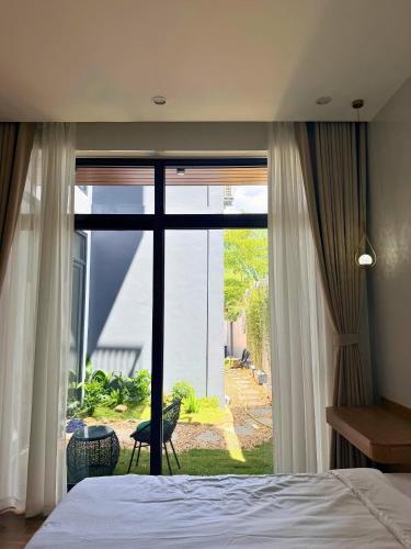 a bedroom with a bed and a large window at Wind Village in Hà Lời
