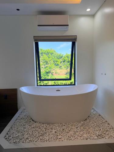 a large white bath tub in a room with a window at Wind Village in Hà Lời