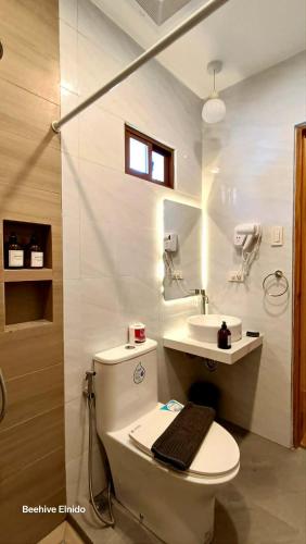 a white bathroom with a toilet and a sink at Beehive El Nido in El Nido