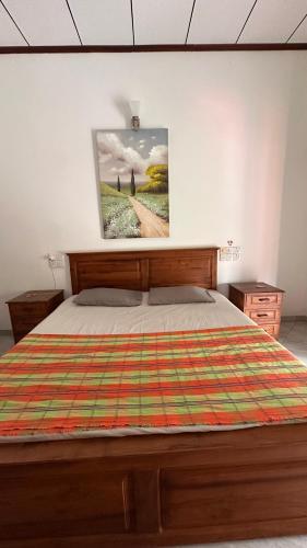 a bedroom with a bed and a picture on the wall at Chamo Villa by DrMocktail in Beruwala
