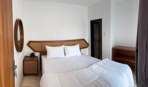 a bedroom with a large white bed and a mirror at Villa Alibaba D3 in Batu