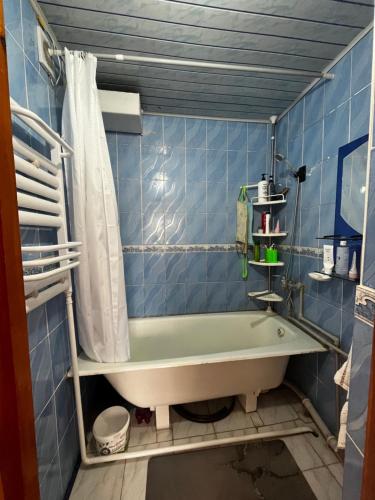 a bathroom with a tub and a blue tiled wall at Aida in Tebykty