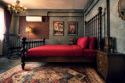 a bedroom with a bed with a red bedspread at Cinematique Boutique Cinema Hotel in Bangkok