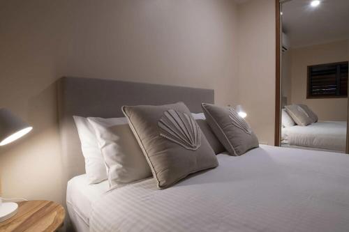 a bedroom with a white bed with pillows and a mirror at Latitude 17 Suite 4 in South Mission Beach