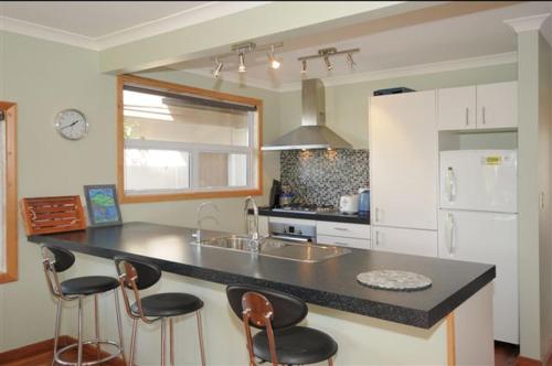 a kitchen with a counter and four bar stools at Te Moana Delight in Waikanae